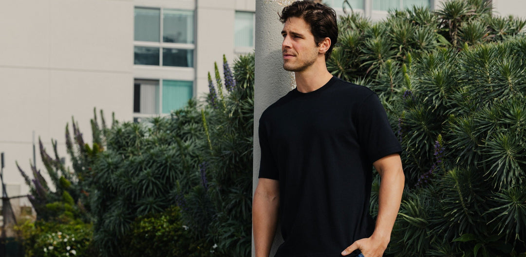 Man standing in lush background wearing a Bamboo Tee in Black