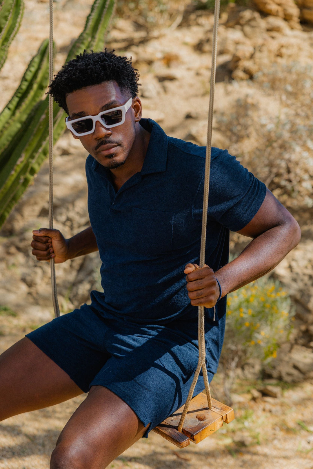 Man on swing in the desert wearing the Coastal Terry Polo and Coastal Terry Short in Navy