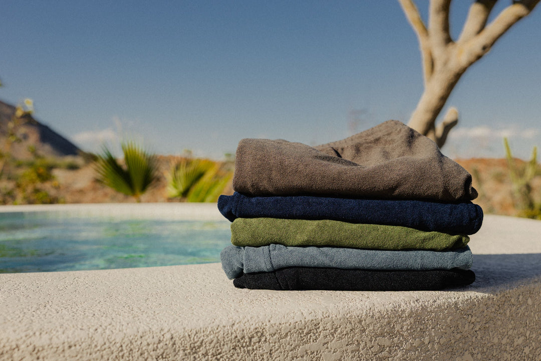 A stack of coastal terry shorts against a lush desert background and pool