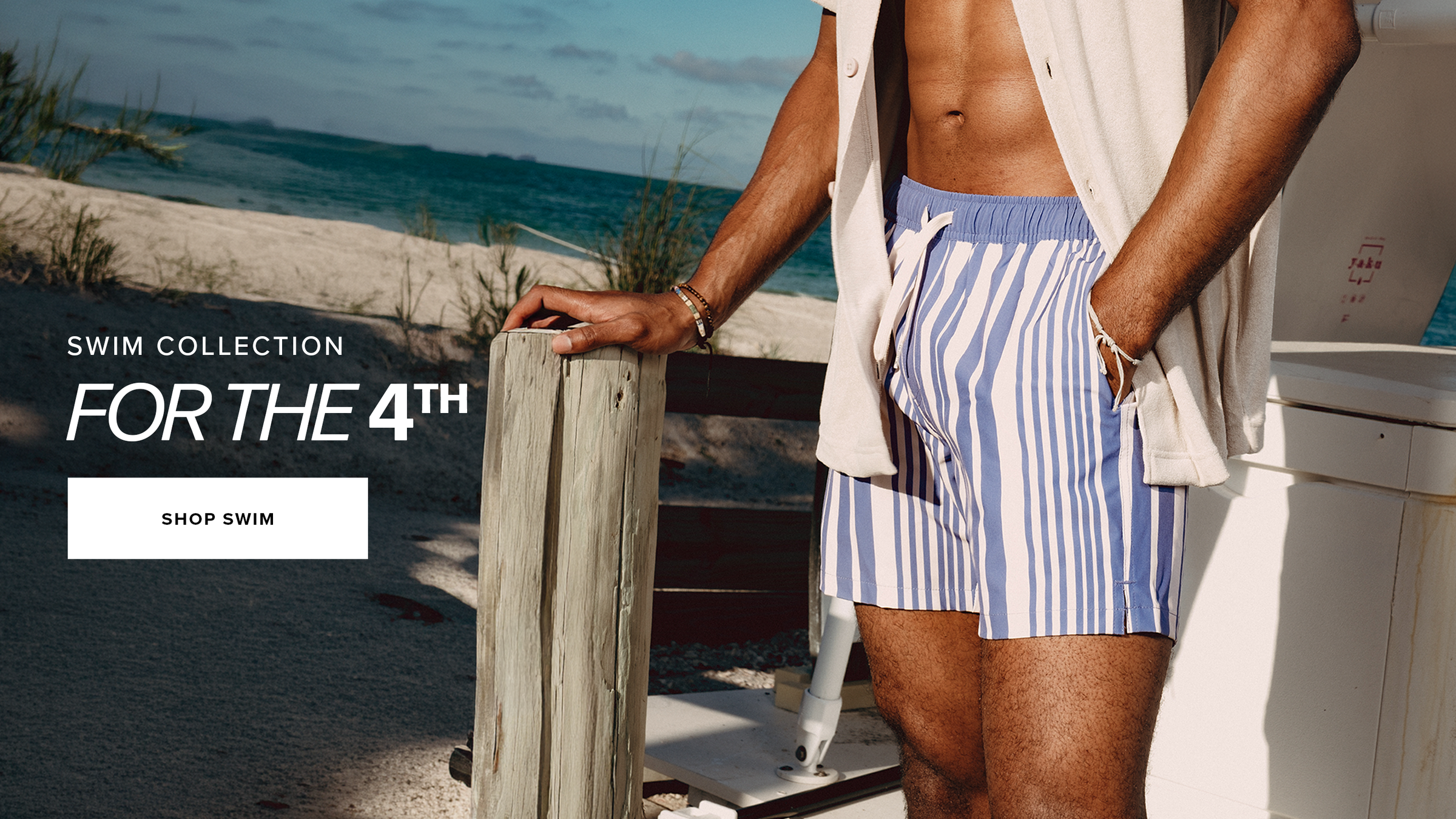 Swim Collection for the 4th. Shop swim. Man wearing Stretch Swim Trunk in Purple Vintage standing on the beach.