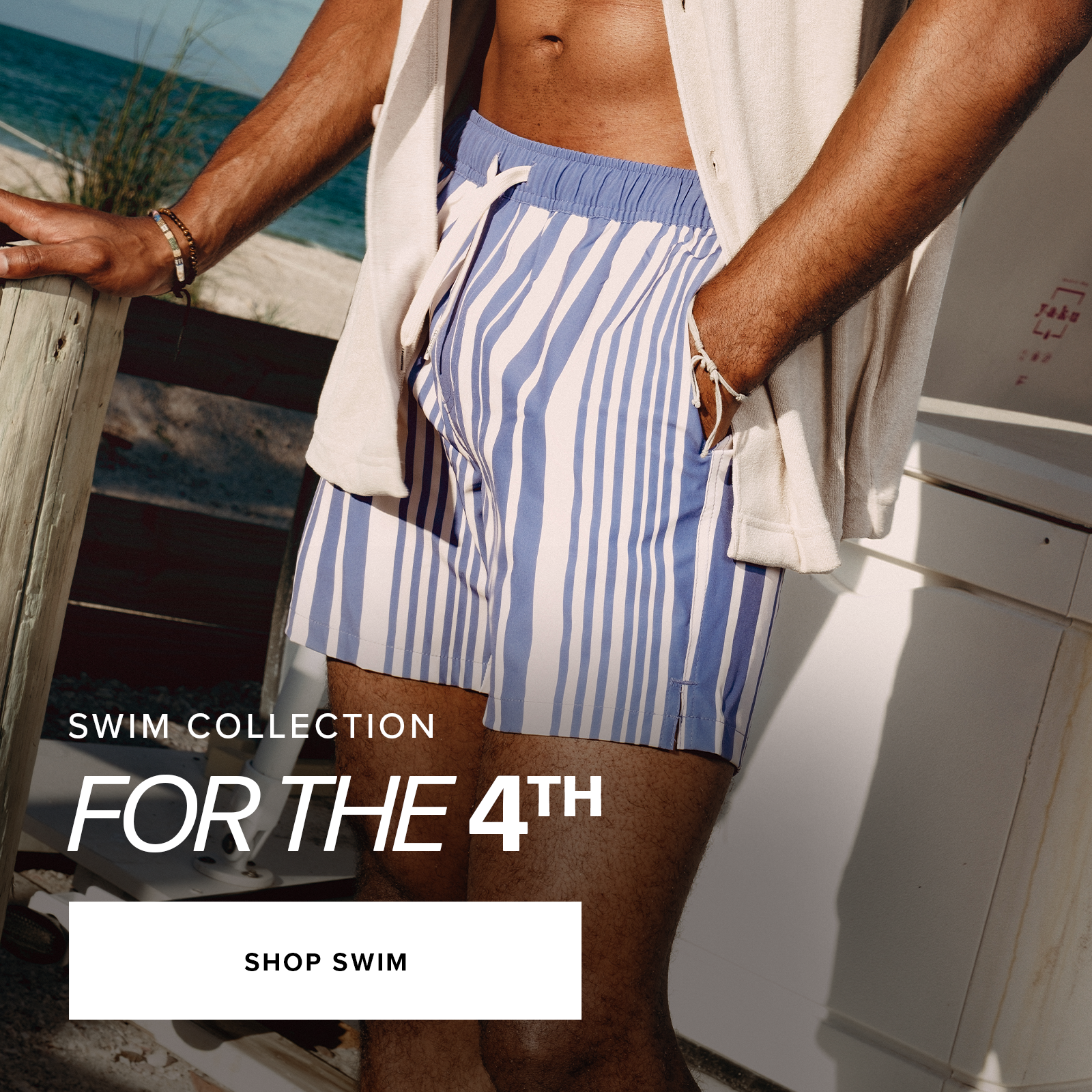 Swim Collection for the 4th. Shop swim. Man wearing Stretch Swim Trunk in Purple Vintage standing on the beach.