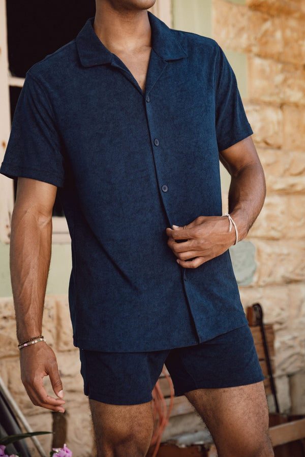 Man wearing a the Coastal Terry Shirt in Navy and Coastal Terry Shorts in Navy standing outdoors.