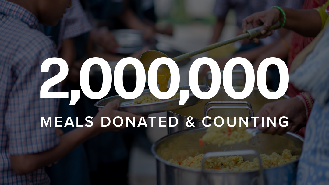 A large white text overlay reading '2,000,000 MEALS DONATED & COUNTING' over a blurred background of people serving food from large metal pots.