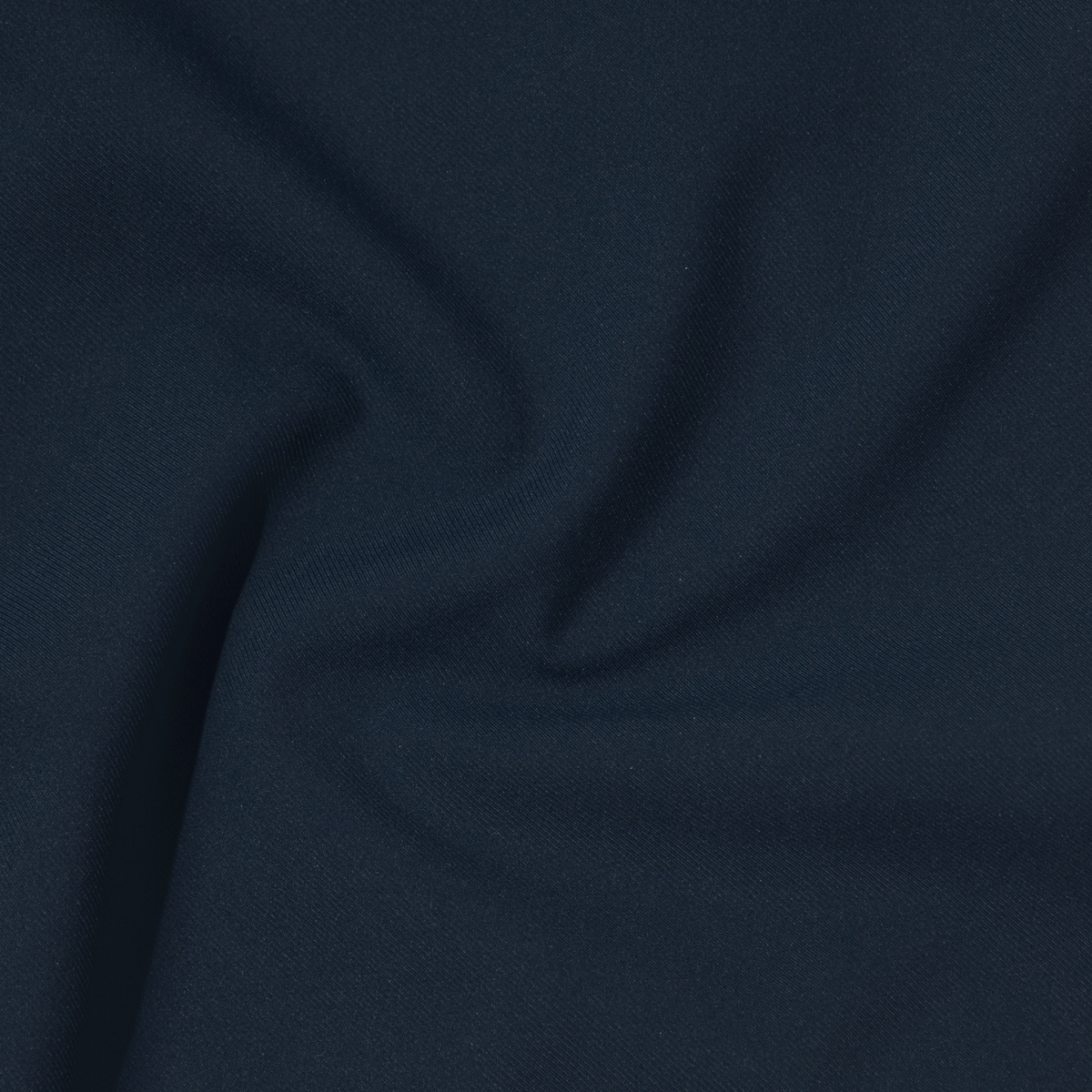Close-up of dark navy blue Hybrid Short fabric with soft folds forming a subtle swirl pattern. The smooth texture and 4-way stretch suggest travel-ready performance, while lighting enhances the gentle curves of this versatile material.