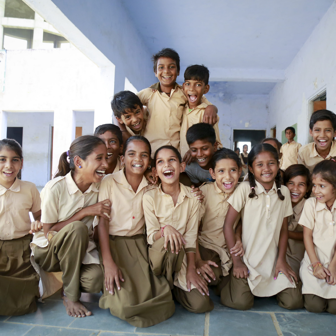 Schoolchildren in uniforms in India laughing and smiling all together