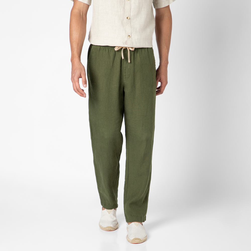 Wearing a beige short-sleeve shirt and olive green Linen Easy Pant, known for its breathability, along with white slip-on shoes. The photo is cropped from the shoulders down against a plain white background.