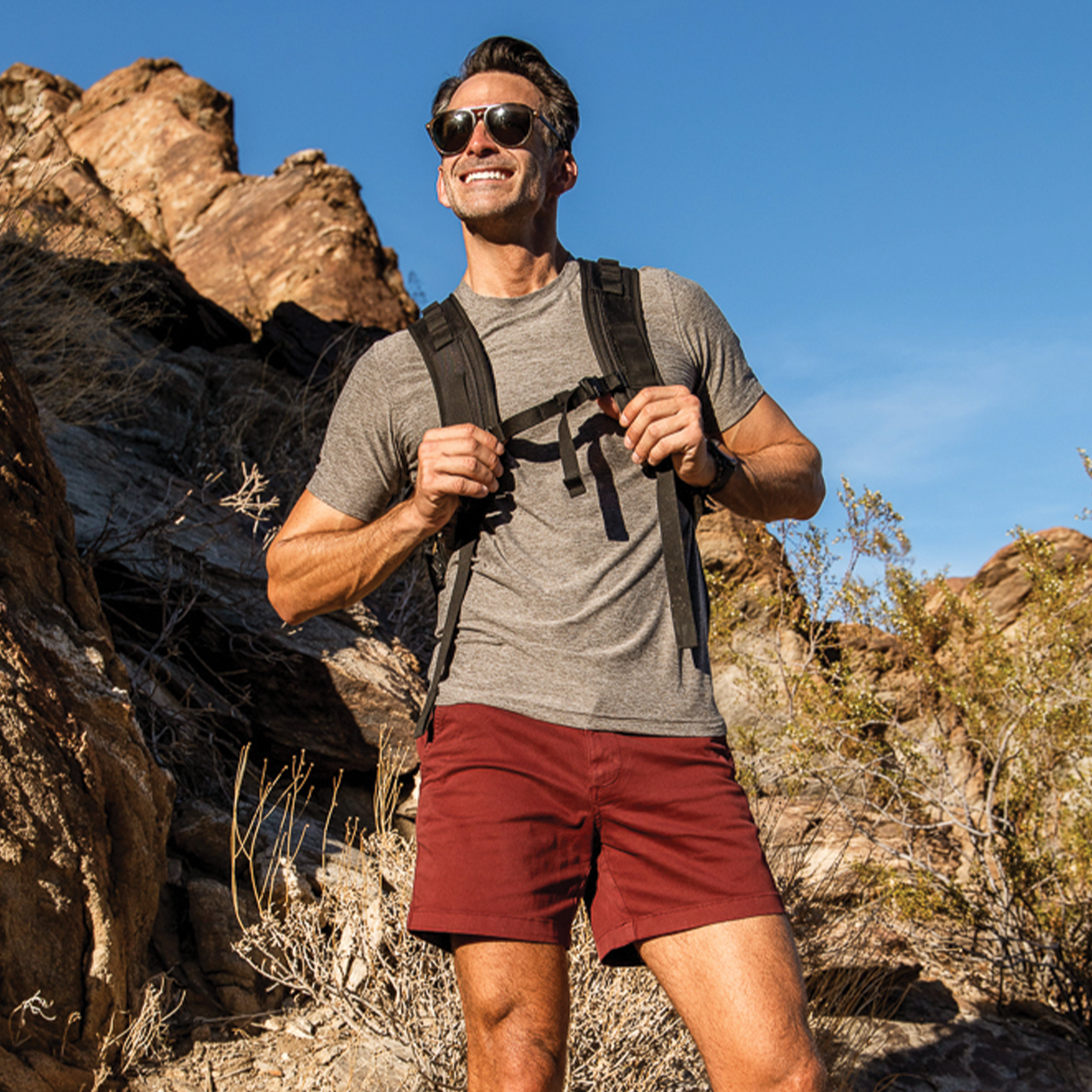 Man hiking wearing Tech Tee Short Sleeve in Grey and Stretch Short 7" in Maroon