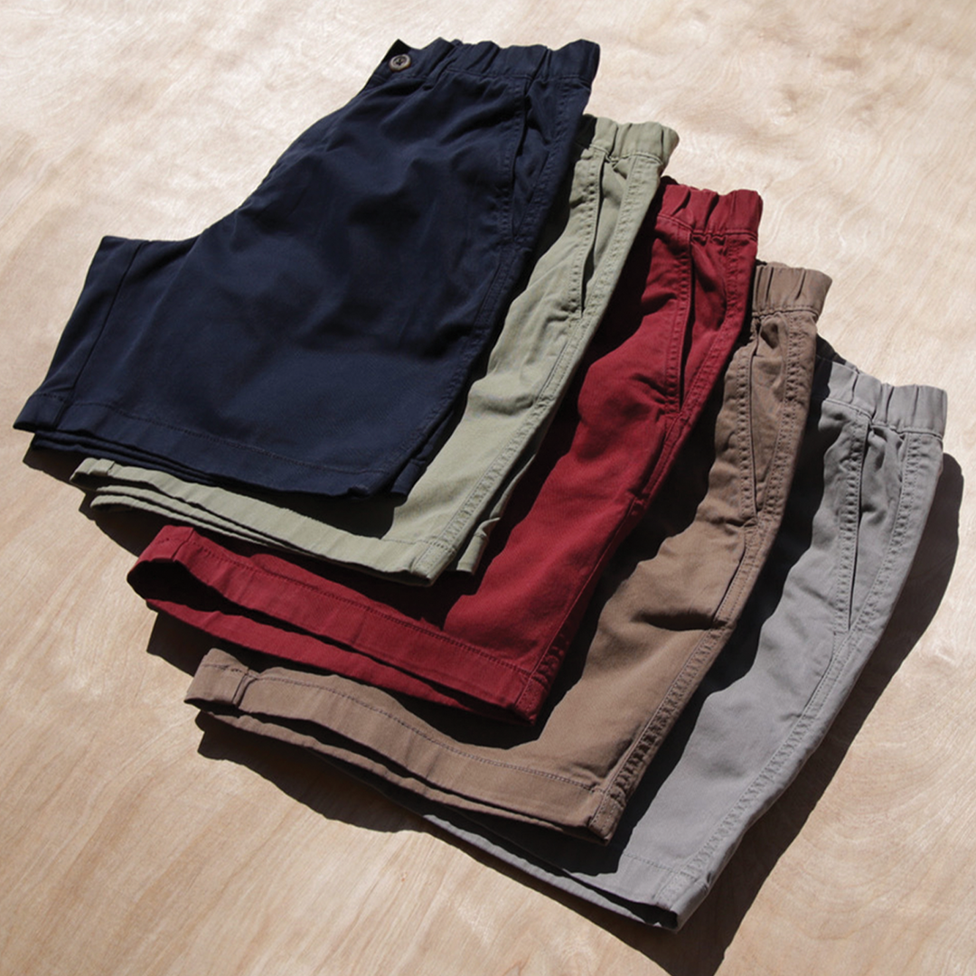 Stretch Short 5.5" stacked on top of each other in colors Navy, Olive, Maroon, Desert, and Grey