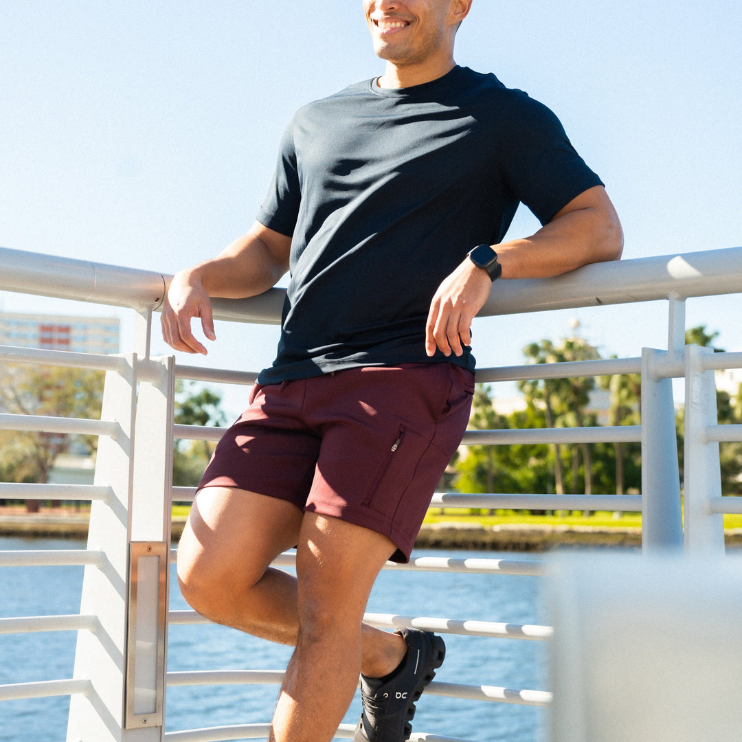 Recharge Short Maroon on man smiling leaning against railing in front of a river
