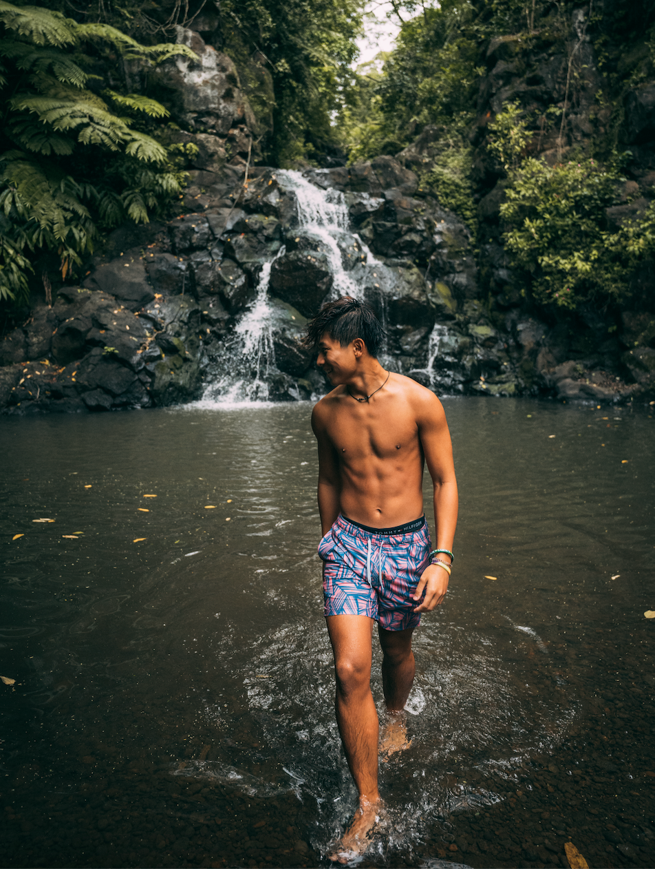 Man walking in water at the bottom of a waterfall wearing Stretch Swim 7" in Breezy