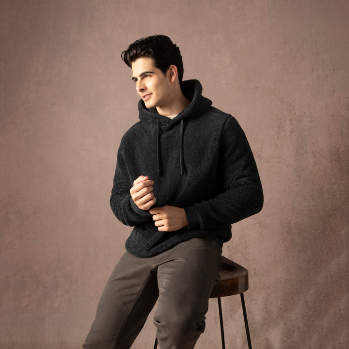 Sherpa Hoodie Black seated on model on backdrop