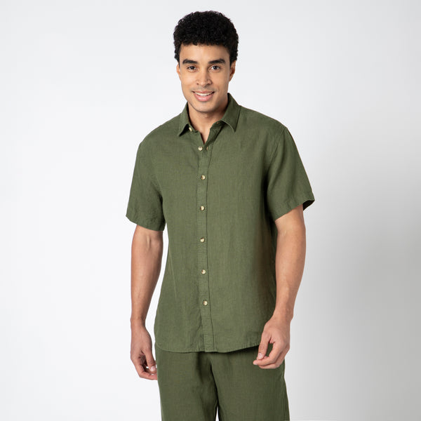 A man smiles against a plain white background, wearing a Fern Linen Short Sleeve Shirt for natural comfort.