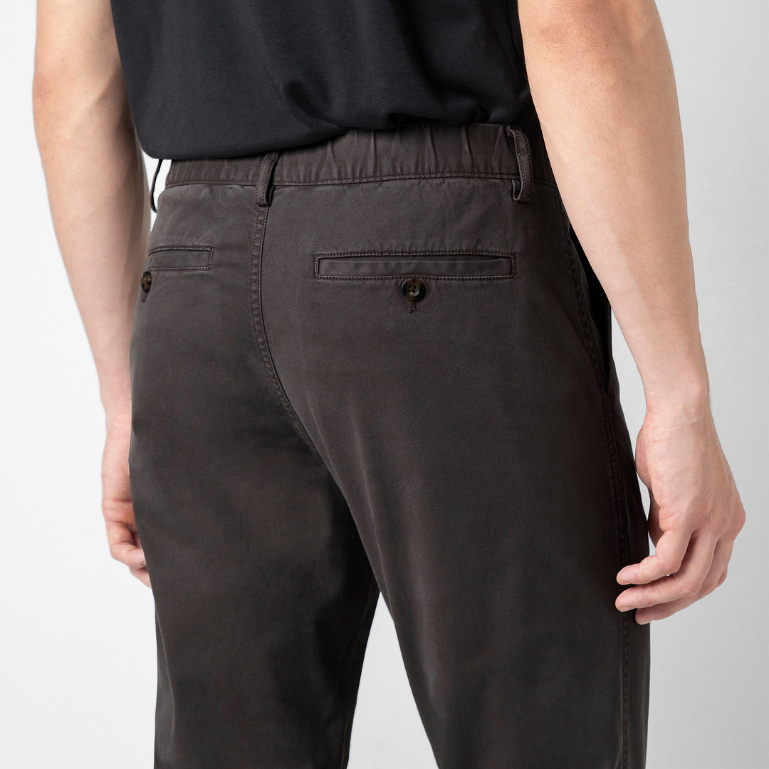 A close up of the back of the Coal Stretch Jogger, showing the buttoned welt pocket and the elastic waistband.