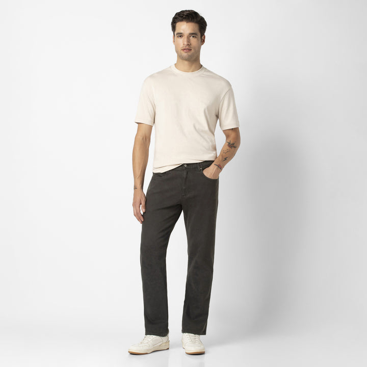 A full body shot of a model wearing the Stretch Travel Jean in Charcoal Black.