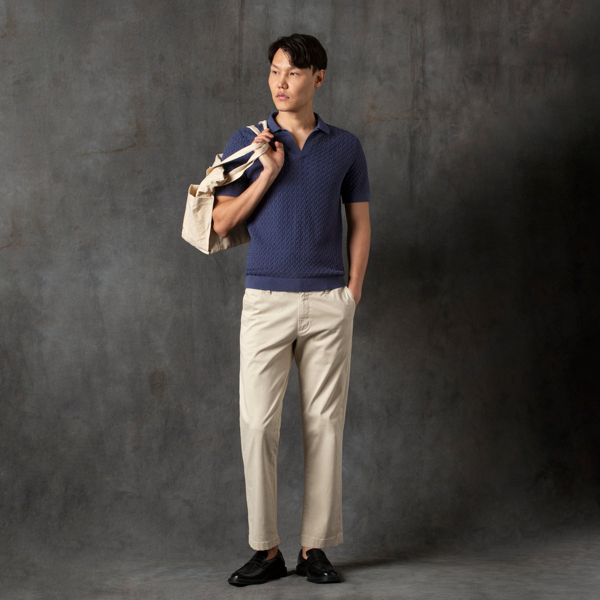 Textured knit Sweater Polo Navy full body on model Charcoal Backdrop and holding tote