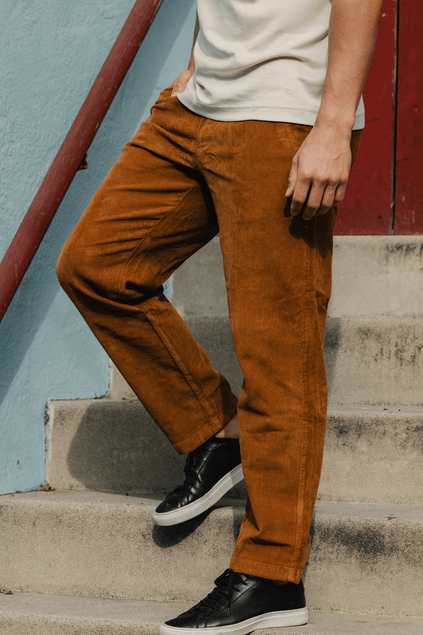 A man walking down stairs wearing the Corduroy Easy Pant in Dark Clay.
