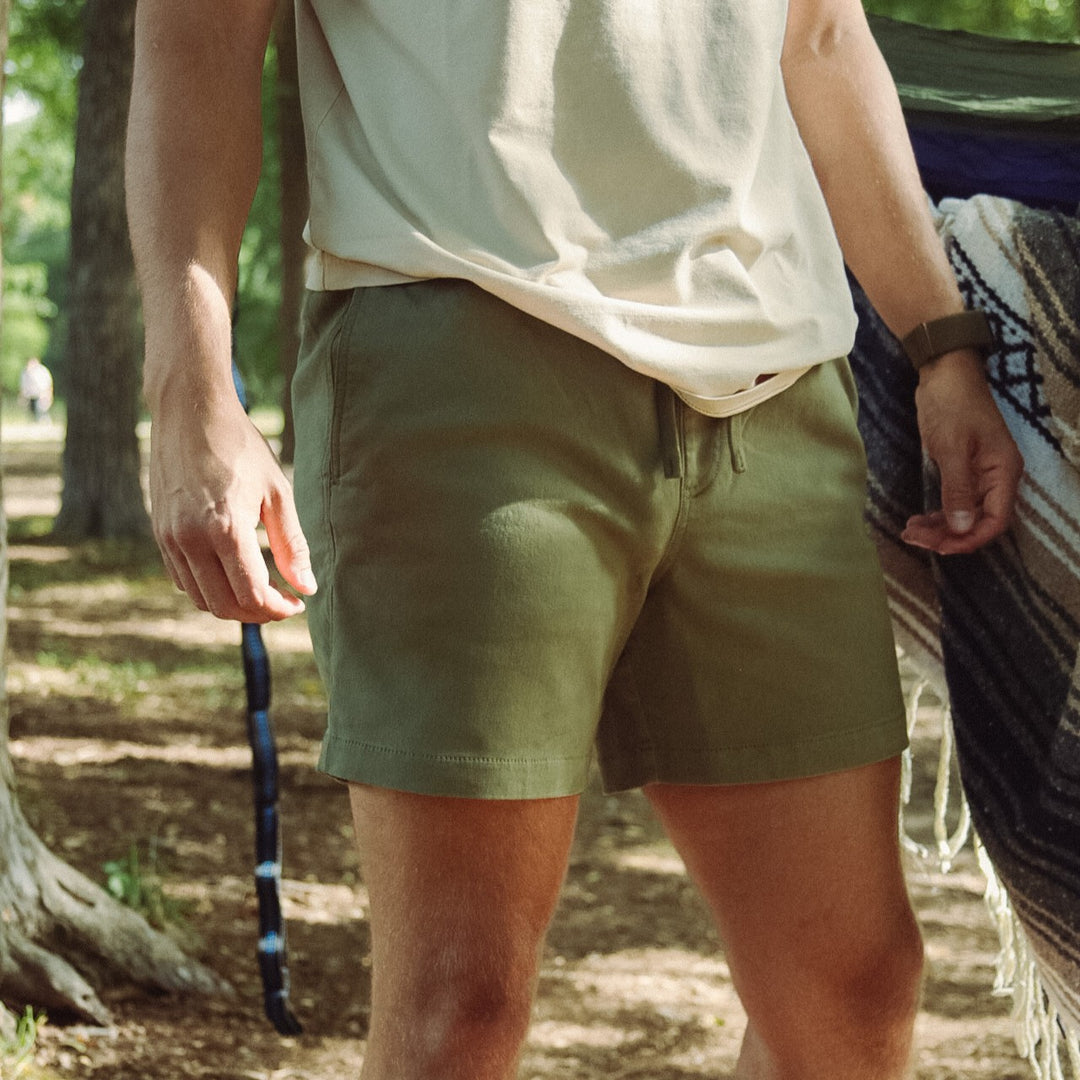 Person wearing Alto Short Olive 5.5" and a white shirt in a forest setting