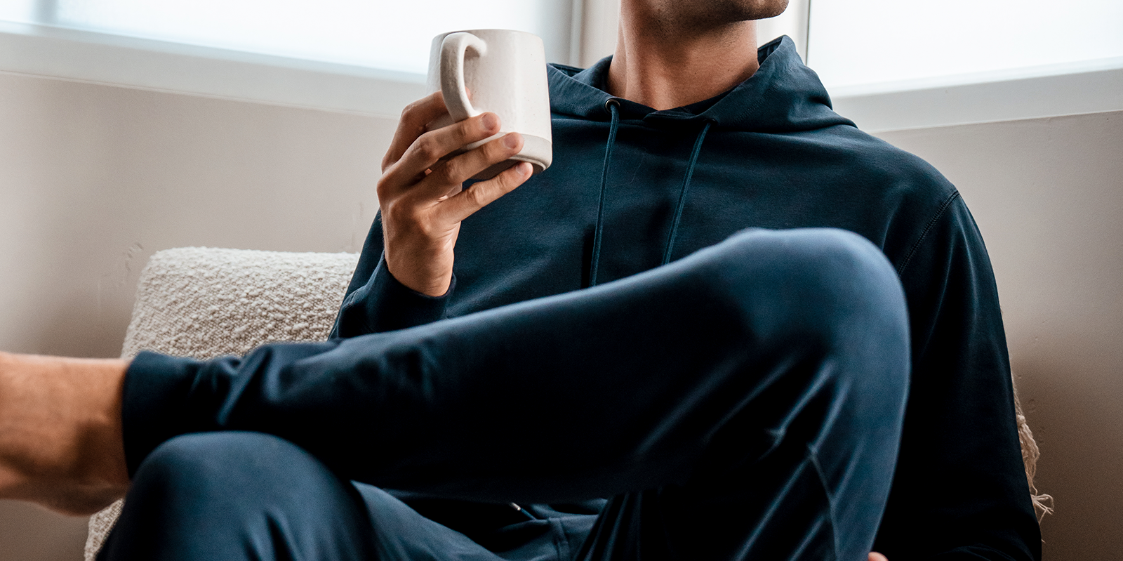 Model wearing Loft Jogger Navy and Loft Hoodie Navy sitting holding coffee cup