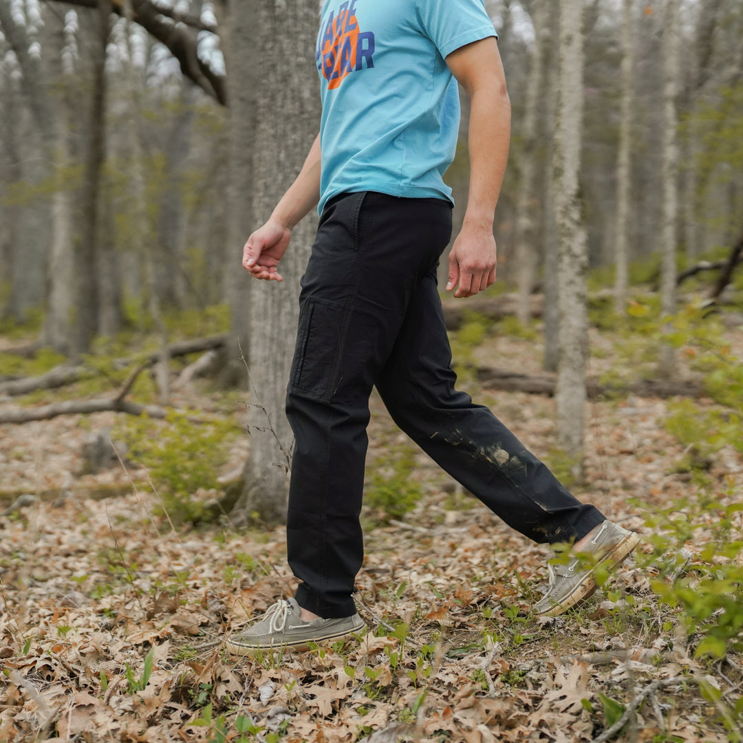 Person walking in a forest wearing a Natural Dye Graphic Tee and Ridge Ripstop Pant in Black