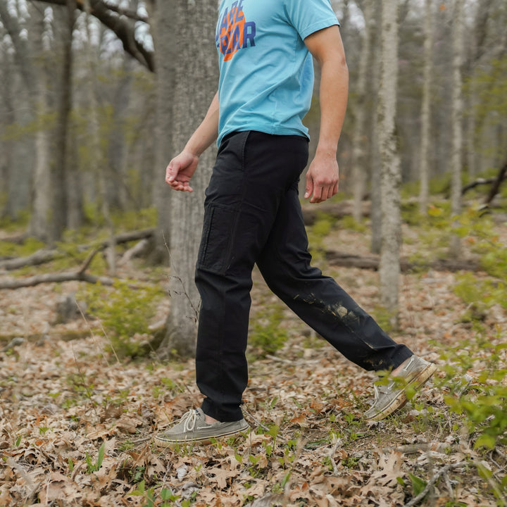 Person walking in a forest wearing a Natural Dye Graphic Tee and Ridge Ripstop Pant in Black