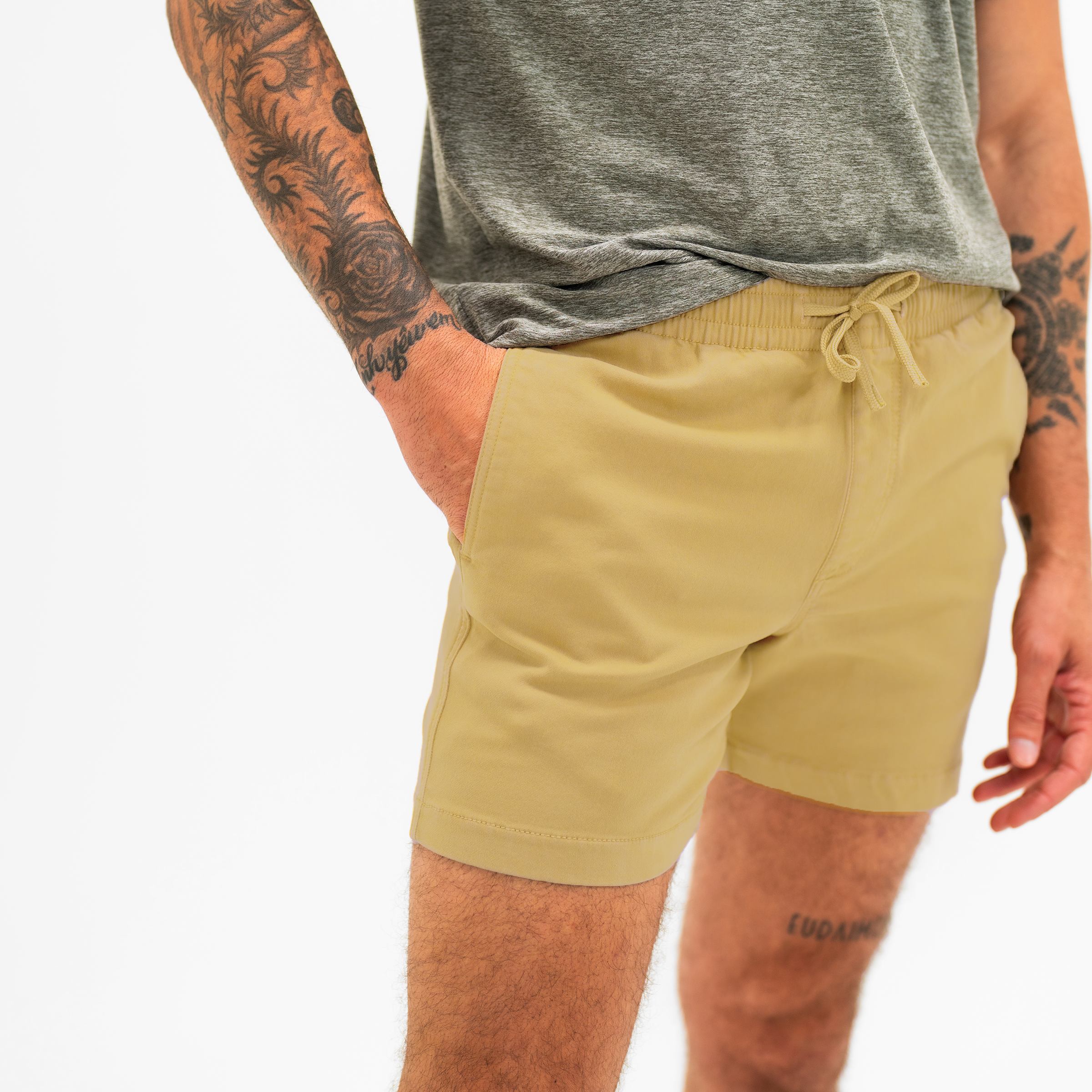 Alto Short 5.5" inseam in Khaki side on model with elastic waistband, fabric drawstring, faux fly, and two front side seam pockets