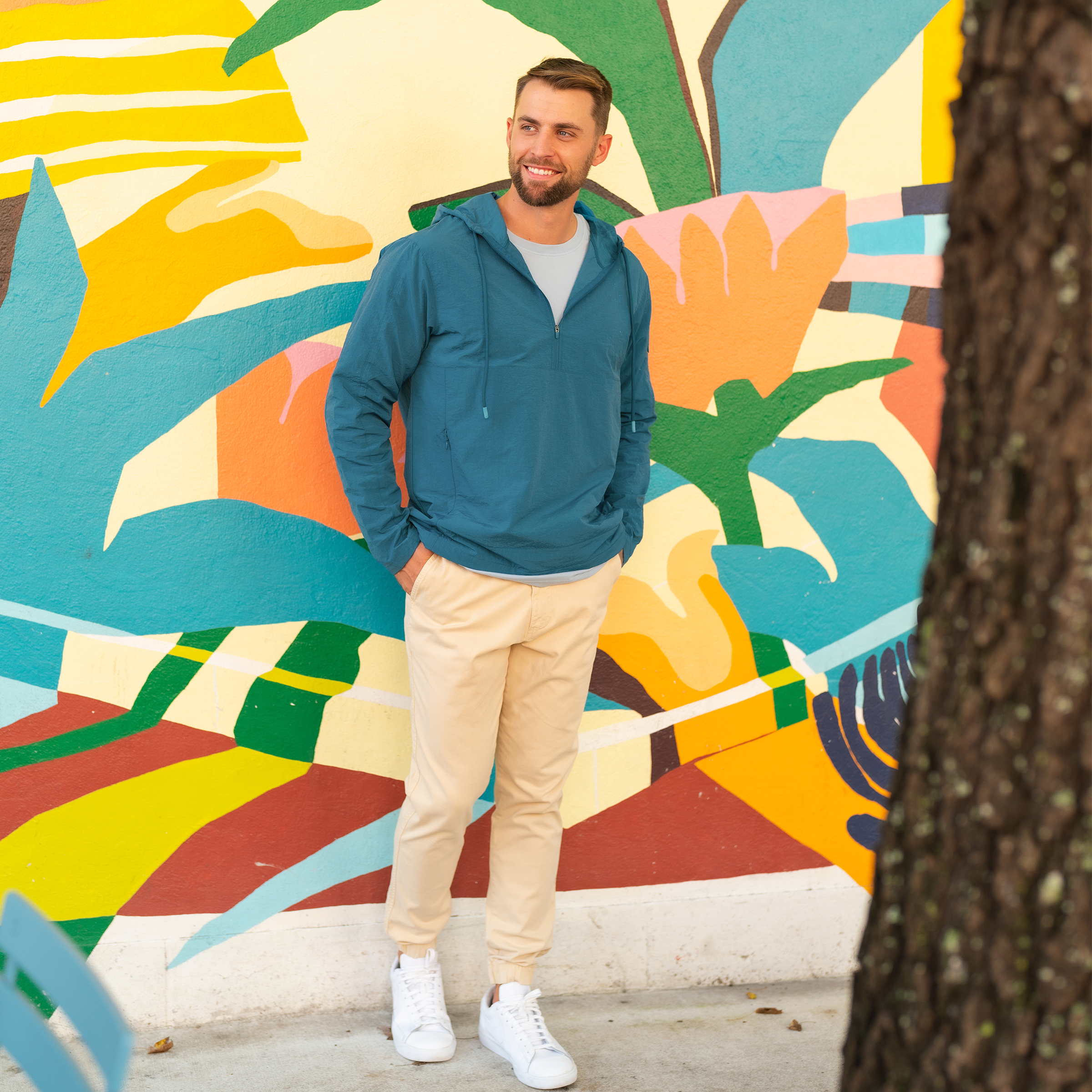 Windbreaker Jacket in Ocean blue on model standing outside in front of brightly colored wall worn with Stretch Jogger in Sand Dune